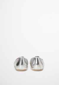 Chaussures de ballet métalliques argentées avec une texture lisse, embout arrondi, petit talon et accent en boucle à l'arrière. Design léger et élégant.