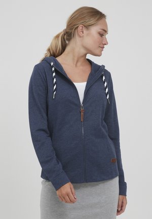 Navy zip-up hoodie made of soft fabric, featuring striped drawstrings, a zipper closure, and a small brown leather logo patch.