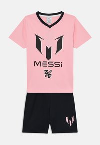 Camiseta de fútbol rosa con detalles en negro, que presenta un gran logotipo y el nombre "MESSI" en el frente, combinada con pantalones cortos negros que exhiben un logotipo en rosa.