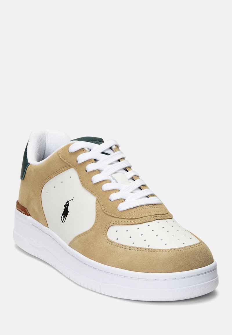 Tan-farbene Wildleder-Sneaker mit weißer Leder-Zehenspitze, Perforationen, grüner Fersenlasche und weißen Schnürsenkeln. Schwarzes Logo an der Seite und weiße Gummisohle.