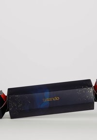 Il packaging di Zalando è di un blu scuro con accenti dorati e glitter, e presenta estremità rosse. Ha una forma rettangolare con una finitura lucida, progettata per l'unboxing.