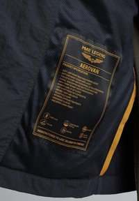 Leichtgewichtige Arbeitsjacke in Marineblau mit strukturiertem Stoff, atmungsaktivem Design, Gummilabel und mehreren Reißverschlusstaschen.