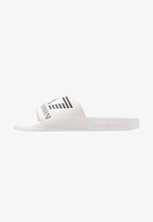 White slide sandal featuring a wide strap with black logo print and horizontal stripes. Textured sole for grip and comfort.