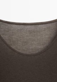 Bruine geribde top met een brede halslijn en een gestructureerde stof. Close-up weergave die de stiknaden rond de kraag benadrukt.