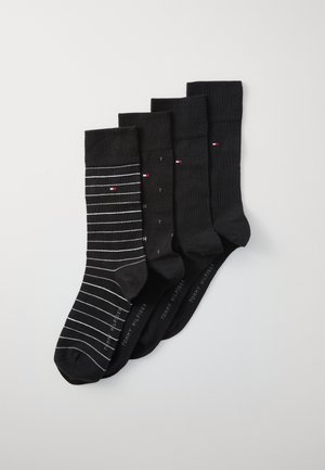 Set črnih nogavic, ki vsebuje štiri pare: enega z belimi črtami, ostali so enobarvni. Vsak par ima rebrast rob in blagovno znamko. Material je bombažna mešanica.