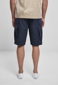 Shorts cargo navy à coupe décontractée, avec deux poches latérales et deux poches arrière. Fabriqués en tissu léger, avec un ourlet roulé.