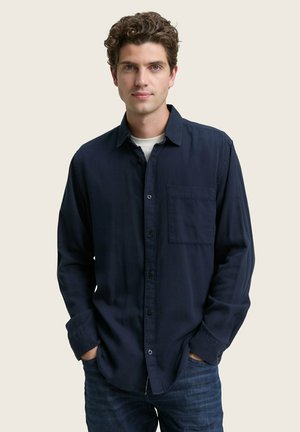 Navy blue shirt made of lightweight fabric, features a button-up design, long sleeves, single chest pocket, and straight-cut hem.