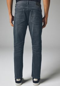Donkergrijze denim jeans met een slim fit, voorzien van twee achterzakken en een lage tailleband. Het materiaal heeft een soepele, licht gestructureerde afwerking.