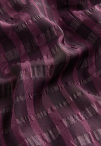 Tekstureeritud kangas, millel on rikkaliku lilla ja musta triibud erineva laiusega, sile kuma ja peen muster.