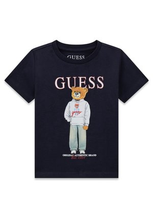 Granatowy T-shirt z niedźwiedziem ubranym w bluzę z kapturem i dżinsy, nazwa marki "GUESS" na górze oraz "Original Authentic Brand Est. 1981" na dole.