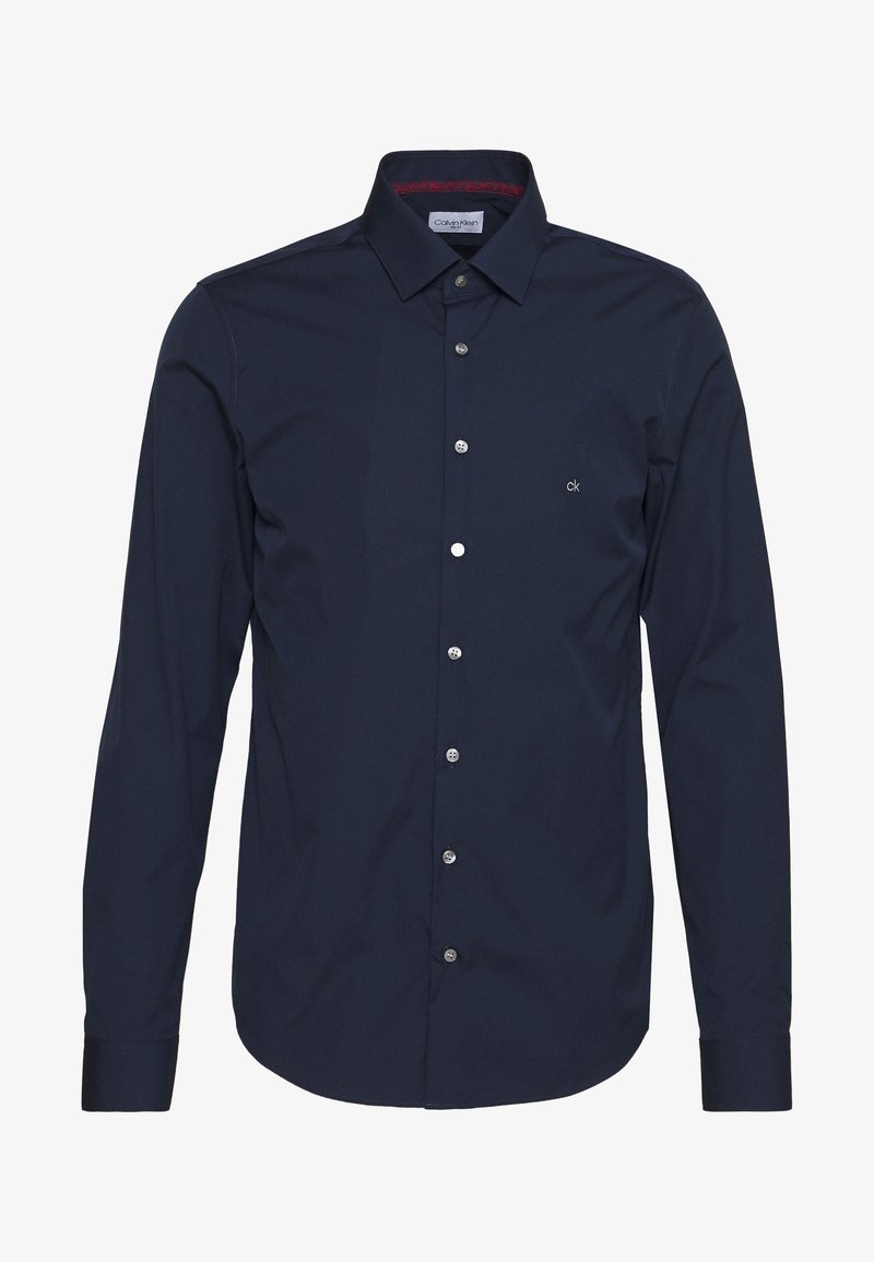 Camisa de manga larga azul marino hecha de una mezcla de algodón. Cuenta con un cuello abotonado, botones plateados y un pequeño logo de CK en el pecho.