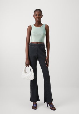 Svijetlozeleni rebrasti crop top, tamno prugaste raširene hlače, bijela prešita torba i ljubičaste sandale s visokom petom. Jednostavan, moderan dizajn.