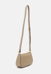 Beige crossbody bag with a curved shape, smooth leather texture, adjustable strap, and gold-tone hardware accents.