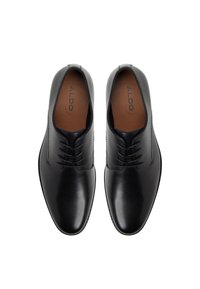 Zapatos de vestir de cuero negro con un acabado suave, punta redondeada, diseño de cordones con cinco ojales y sutiles detalles de costura en la parte superior.