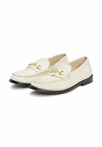 Witte leren loafers met goudkleurige hardware en een gestikt ontwerp, met een ronde neus en een zwarte platte zool.
