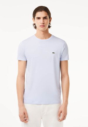 T-shirt azzurro corto in cotone morbido, con un piccolo logo ricamato verde sul petto e collo rotondo.