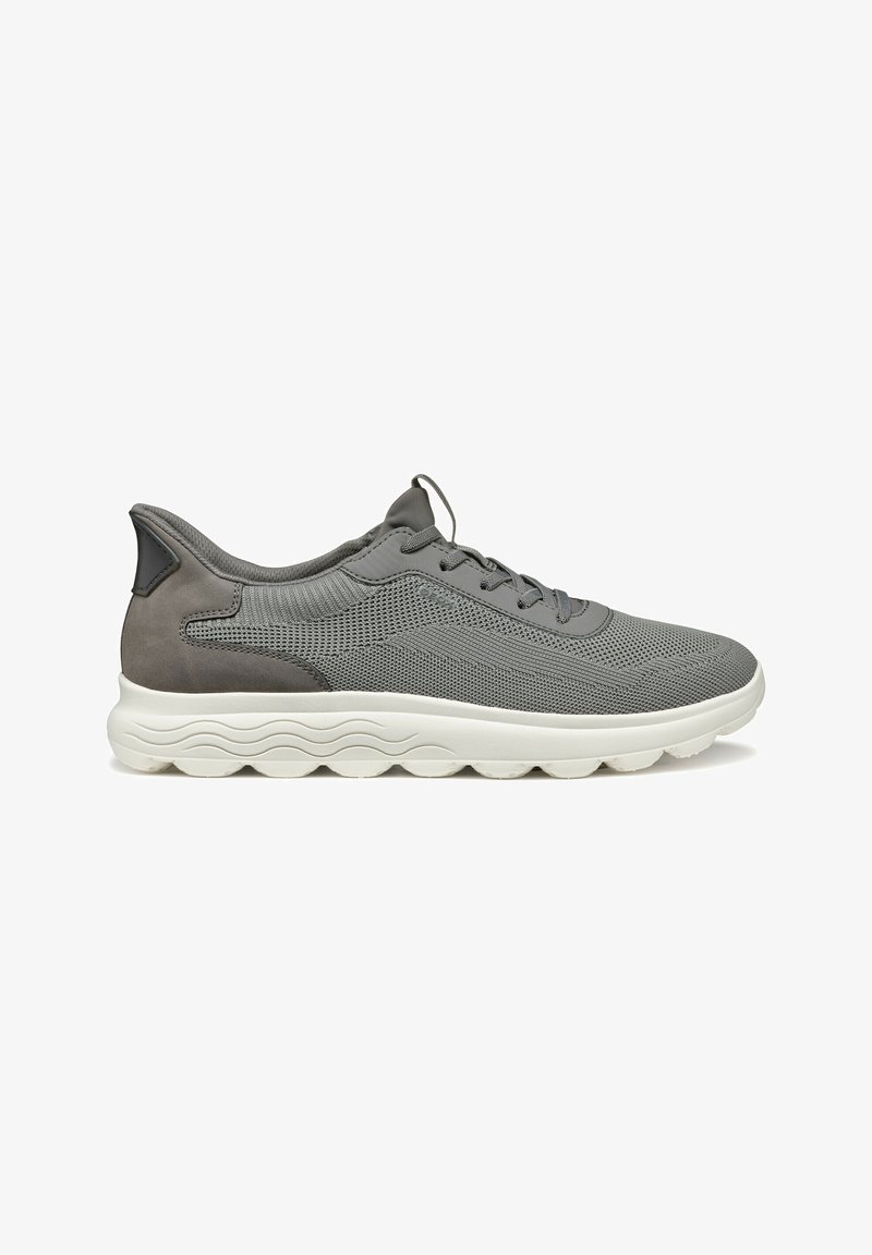 Graue Mesh-Sneaker mit einem Wildleder-Ferseneinsatz, runden Schnürsenkeln und einer strukturierten weißen Sohle mit wellenartigen Mustern. Atmungsaktives Design für hohen Komfort.