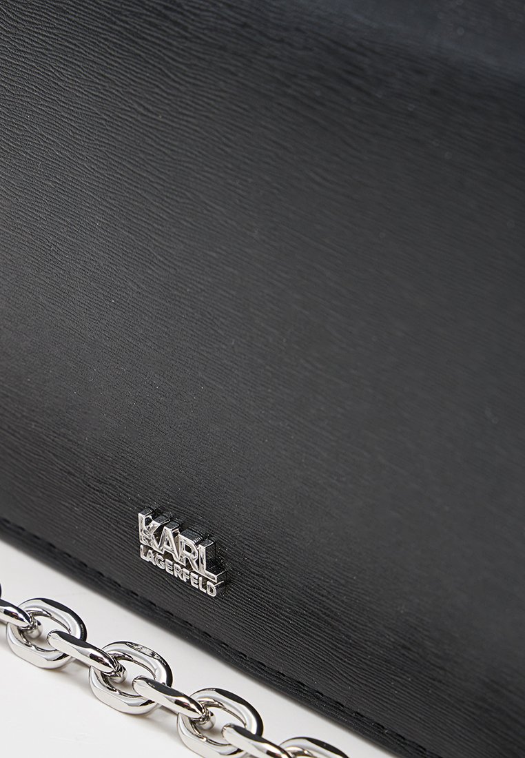 Sac à main en cuir noir avec une finition texturée, doté d'une bandoulière en chaîne argentée et d'une plaque logo argentée portant l'inscription "KARL LAGERFELD."