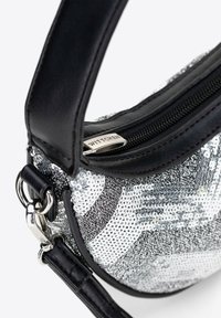 Borsa a tracolla in pelle nera con paillettes argento, forma curvata, chiusura con zip, accessori in metallo e tracolla attaccata. Etichetta del brand visibile.