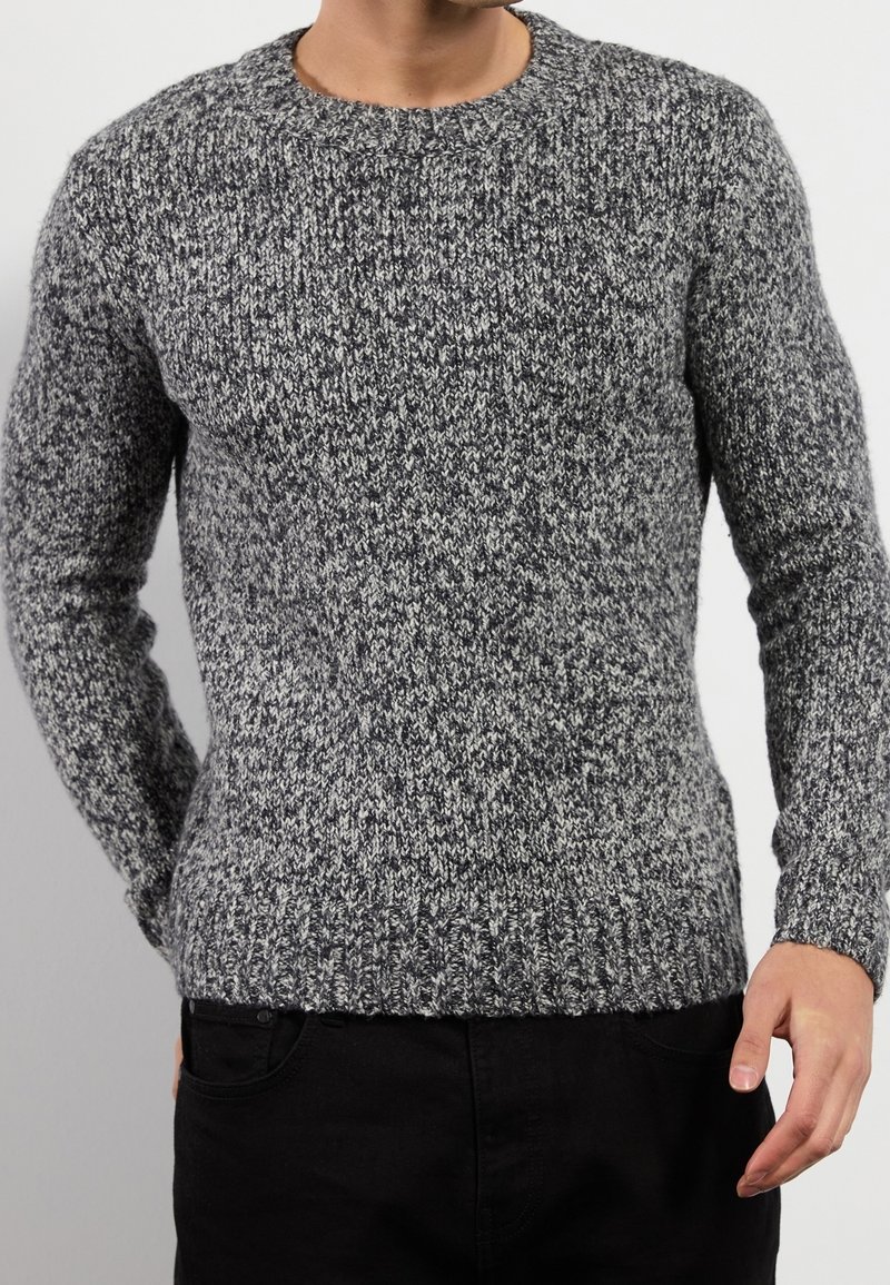Grau gestrickter Pullover mit Rundhalsausschnitt und strukturiertem Muster. Rippbündchen und Saum, die eine Mischung aus dunklen und hellen Grautönen aufweisen.