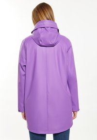 Giacca impermeabile viola con cappuccio, caratterizzata da una texture liscia, bottoni a scatto e un dettaglio testuale sul retro. Maniche lunghe e vestibilità comoda.