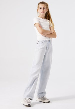 Lichtgewassen wijde jeans met een relaxte pasvorm, gecombineerd met een aansluitend wit geribbeld t-shirt en grijze sneakers. Minimalistisch ontwerp, geen patronen.