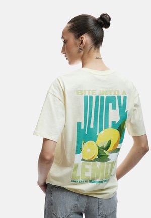 Lysegul bomulds T-shirt med grafisk tryk af citroner og tekst; løs pasform og korte ærmer med rund halsudskæring.