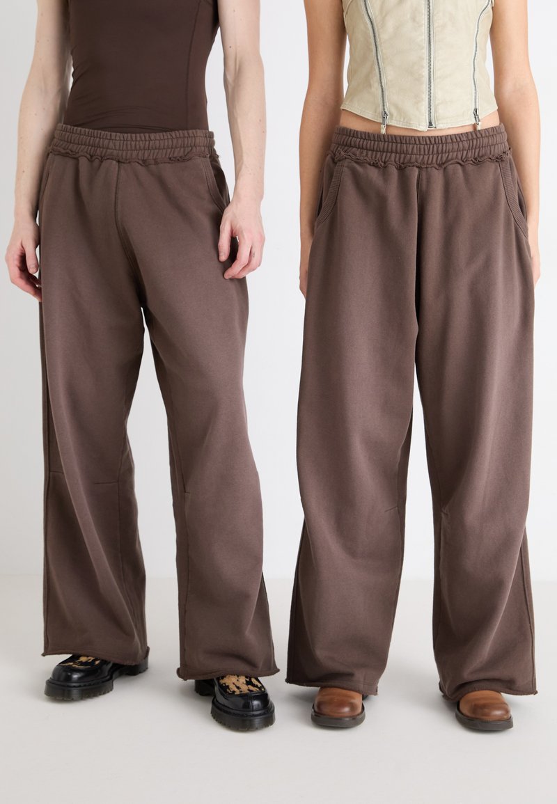 Braune weite Sweatpants mit elastischem Bund und Seitentaschen, aus weichem Stoff mit glatter Textur gefertigt.