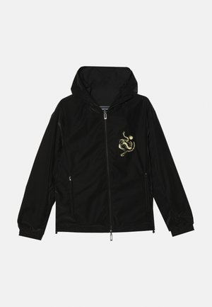 Sort zip-front jakke med hætte, med et guldfarvet broderet design på venstre bryst, elastiske manchetter og to sidelommer.