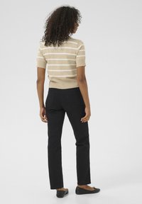 Beige raitapaita lyhyillä hihoilla, yhdistettynä mustiin slim-fit-housuihin ja mustiin balettitossuihin. Pehmeä rakenne ja perusdesign-elementit.
