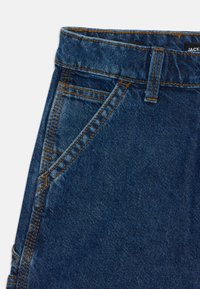 Džínsy z denimu s tmavomodrým praním, s vysokým pásom, oranžovým prešitím a prednými vreckami. Hladká textúra s klasickým dizajnom.