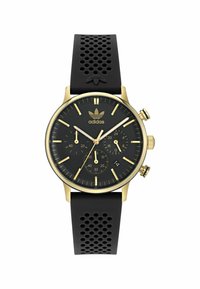 Montre chronographe noire avec accents dorés, bracelet en caoutchouc avec des trous, cadran noir, marques d'heures dorées et logo à la position de 12 heures.