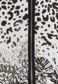 Tissu noir et blanc présentant un mélange de taches de léopard et de motifs de feuilles tropicales, avec une fermeture éclair noire centrale et des dessins en ligne détaillés.