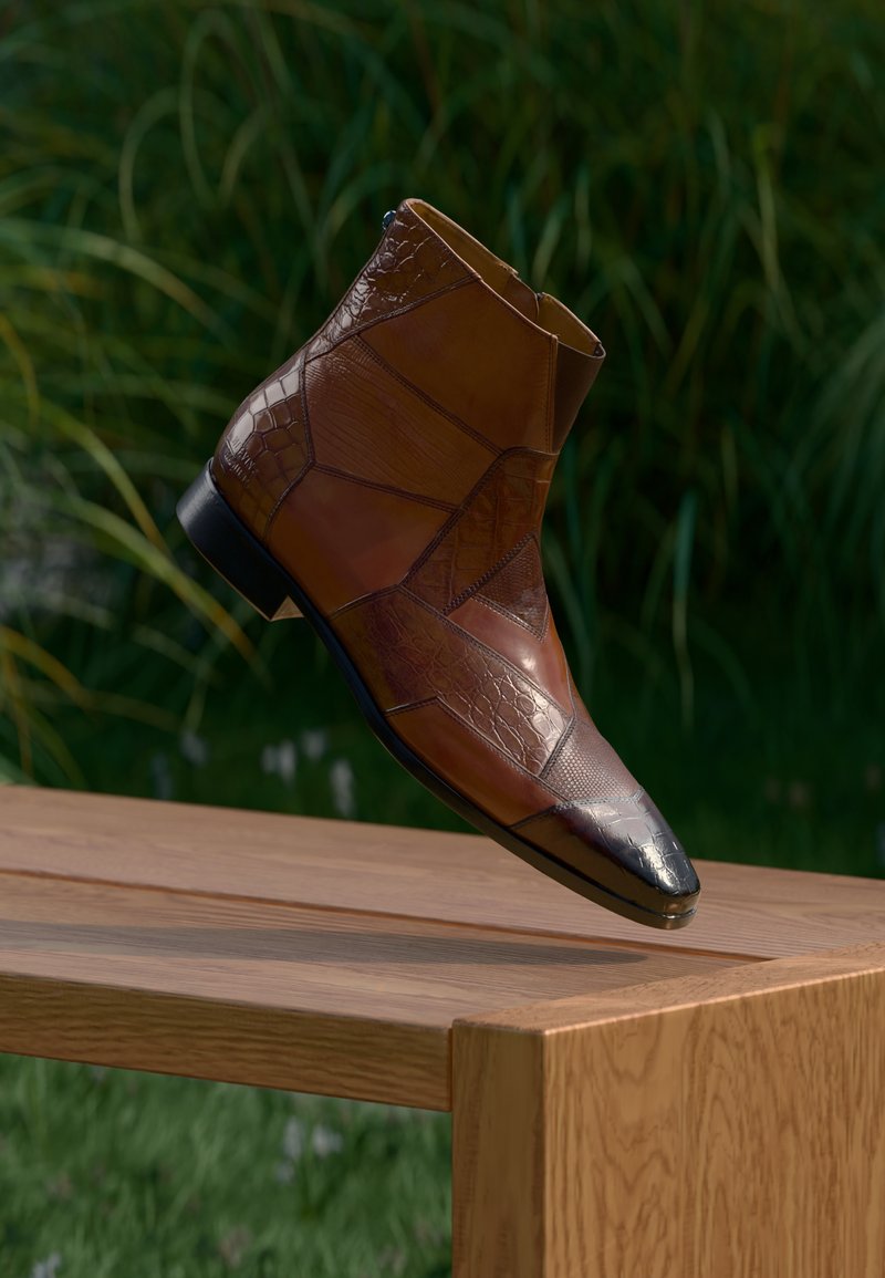 Bottine en cuir marron avec design patchwork et bout pointu noir, flottant au-dessus d'un banc en bois dans un cadre extérieur.