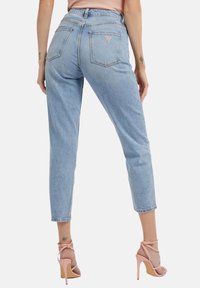 Lichtblauwe high-waisted jeans met een rechte snit, voorzien van een rood merklogo op de achterzak en een subtiele vervaagde textuur.