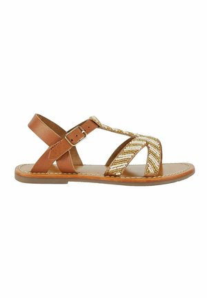 Sandale en cuir marron avec des lanières croisées et un accent métallique tissé. Elle dispose d'une boucle ajustable et d'une semelle plate.