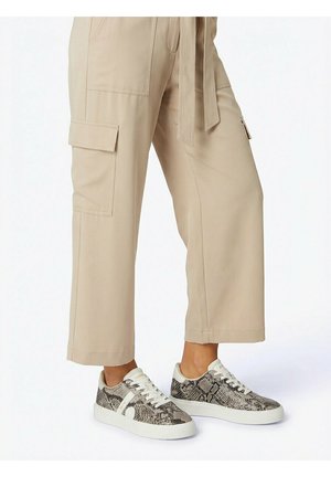 Beige cropped cargobroek met zijzakken, gedragen met lage sneakers met grijzige en zwarte slangenprint en witte zolen.