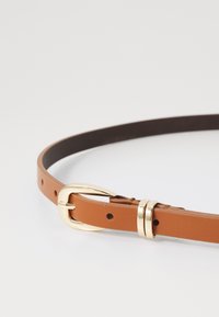 Cintura in pelle marrone con fibbia in metallo dorato, caratterizzata da una superficie liscia e fori perforati per la regolazione. La fibbia presenta un design a doppio anello.