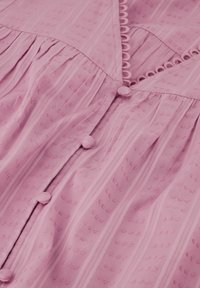 Roze katoenen jurk met verticale strepen, textuurstof, ronde knopen en een decoratieve haakwerkafwerking langs de halslijn.