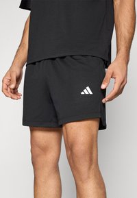 Μαύρο αθλητικό σορτς από διαπνέον πλέγμα ύφασμα, με ελαστική μέση και λευκό λογότυπο Adidas στην αριστερή πλευρά.