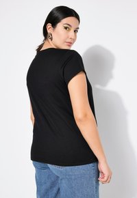 Zwarte T-shirt met korte mouwen, een ronde halslijn en zachte katoen, gecombineerd met lichtblauwe spijkerbroek.