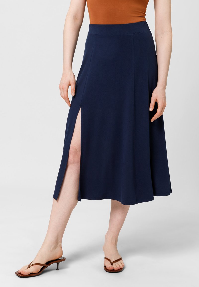 Gonna midi blu navy con design svasato, realizzata in tessuto morbido, caratterizzata da uno spacco alto su un lato e una vita elasticizzata.