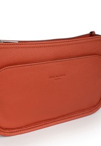 Borsa in pelle arancione con finitura testurizzata, dotata di chiusura con zip e una tasca frontale impressa con "HEXAGONA PARIS." Forma rettangolare semplice.