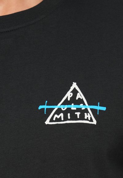 Melna kokvilnas t-kreklu ar trīsstūrveida grafisko dizainu. Iespēro baltu un zilu tekstu ar pāri svītrotu līniju. Gluda faktūra, apaļa kakla izgriezums.