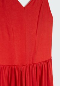 Abito rosso con scollatura a V, busto strutturato e gonna arricciata. Realizzato in tessuto liscio con una consistenza morbida.