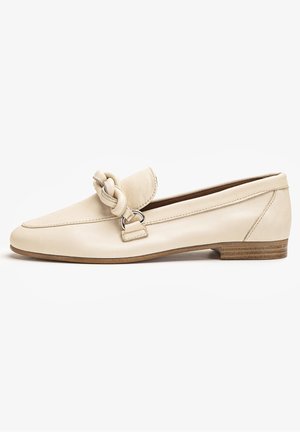Kermanväriset nahkaiset matalat loaferit, joissa on matala puukorko ja koristeellinen punottu remmi päällä.