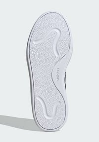 White rubber shoe sole with textured surface and wave pattern; features "adidas" branding; rounded shape with smooth edges.