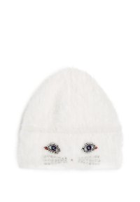 White faux fur beanie featuring embroidered eye design and rhinestone accents on the front, with a rounded top and textured finish.