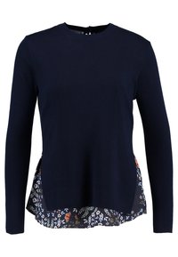 T-shirt à manches longues bleu marine avec un ourlet à motifs floraux, dotée d'un col rond et d'une ouverture en forme de serrure au dos. Texture en tricot douce.