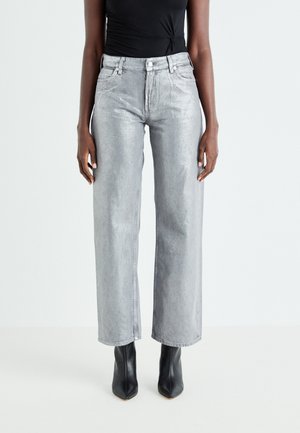 Jean large en denim gris avec une taille haute, un léger éclat, un design à cinq poches et une fermeture à bouton en métal, associés à des bottes à talons noires.